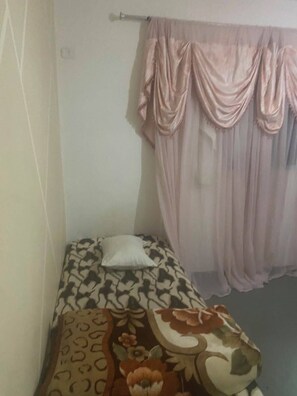 A small room with a bed, a pillow, a curtain, and a wall socket. - Dar Massmoudi (Tunis)