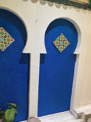 A building with two blue doors, each with a decorative tile above the door. - Dar Massmoudi (Tunis)