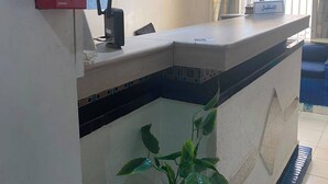 A reception desk with a fire alarm, a potted plant, and a window with curtains. - Dar Massmoudi (Tunis)