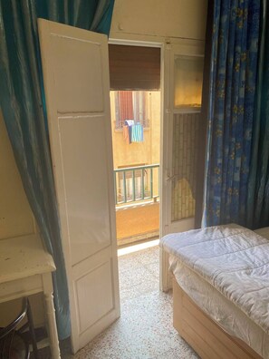 A bedroom with a bed, a door leading to a balcony, and a chair. - Dar Massmoudi (Tunis)