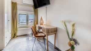 A room with a desk, chair, and a flat-screen TV mounted on the wall.