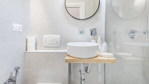 A modern bathroom with a round mirror, a sink, and a shower.
