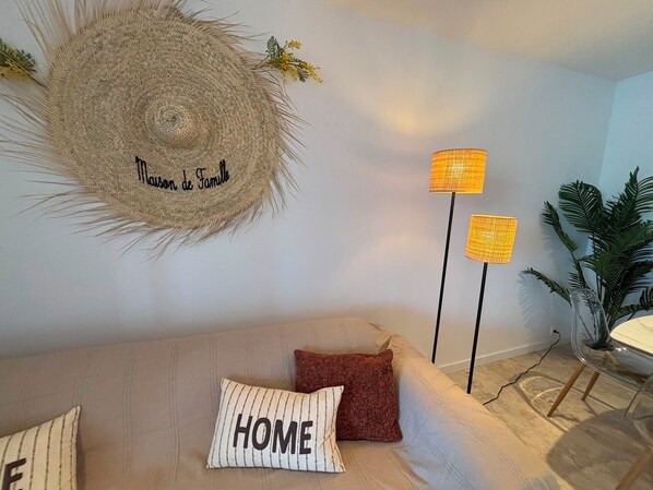 Ein Wohnzimmer mit einer Couch, zwei Lampen, einer Wanddekoration und einem Blumentopf.