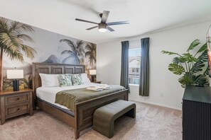 A bedroom with a bed, a nightstand, a bench, a ceiling fan, a window with curtains, and a wall mural. - 4735 Solterra Resort 4BR Pool House near Disney (Davenport)