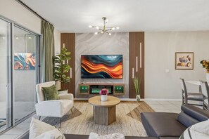 Ein modernes Wohnzimmer mit Flachbildfernseher, Kamin, Sofa, Couchtisch und Essbereich.