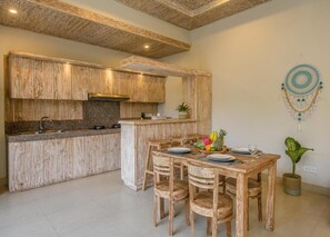 Eine Küche mit Holzausstattung, einer zentralen Kochinsel und einem Essbereich mit Tisch und Stühlen.