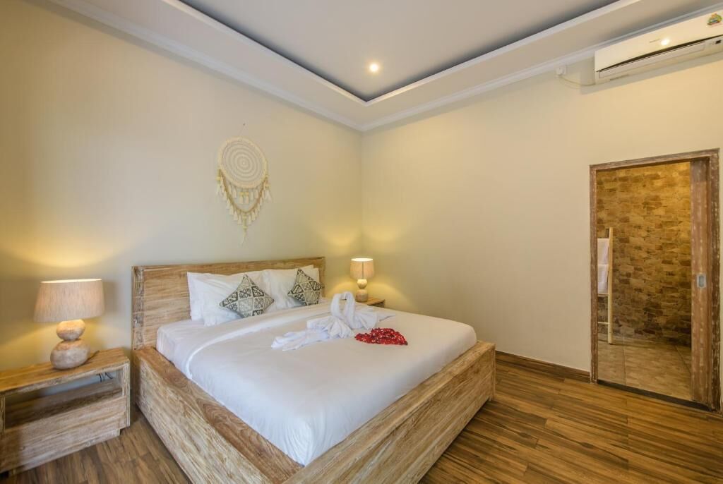 A hotel room with a wooden bed, bedside lamps, a wall decoration, and a door.