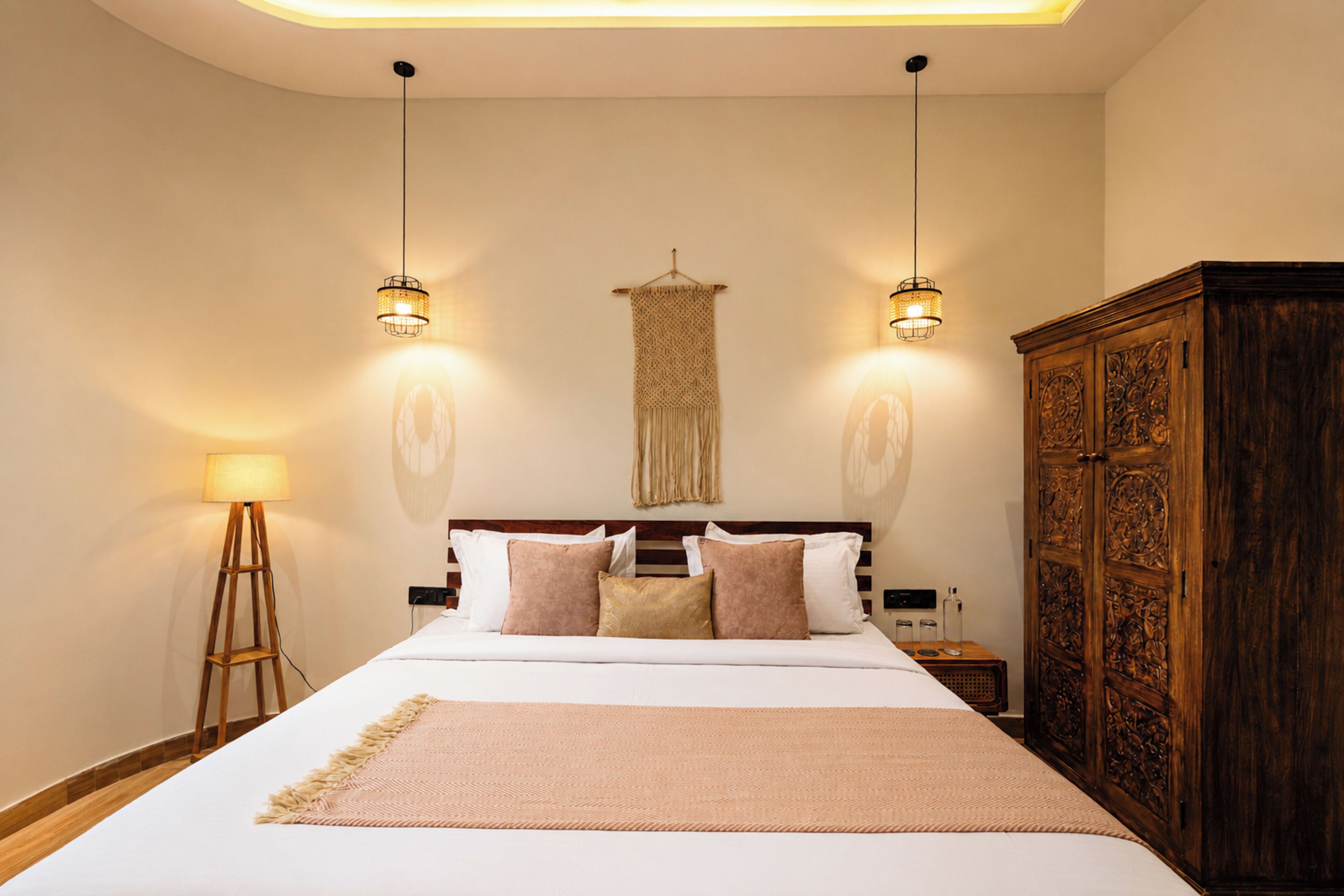 Habitación de hotel con una cama grande, dos lámparas de pared, un armario de madera y una mesita de noche con lámpara.