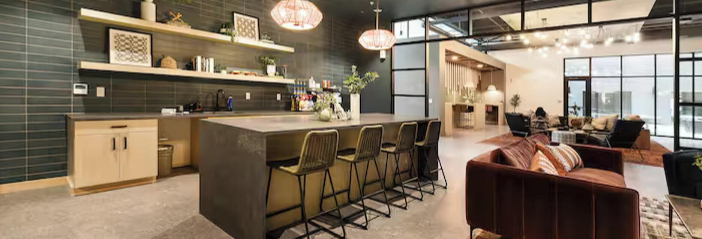 A modern kitchen with a central island, bar stools, and pendant lighting.