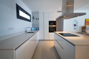 A modern kitchen with white cabinetry, a built-in oven, and a window above the sink. - Luxury 2-Bedroom Apartment with Ocean View in Marbella, Altos de los Monteros (Marbella)