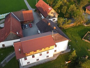 Ein großes, weißes Gebäude mit rotem Dach, umgeben von grünen Rasenflächen und Bäumen.