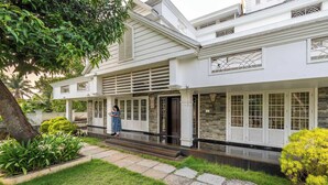 Een tweelaags huis met een overdekte veranda, stenen trappen en een verzorgd gazon.