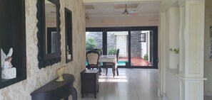 A hallway with a dining area, a ceiling fan, and a view of the outside. - Family Friendly Private Pool Villa, Kochi Near Kadamakudi and Lulu (Varapuzha)