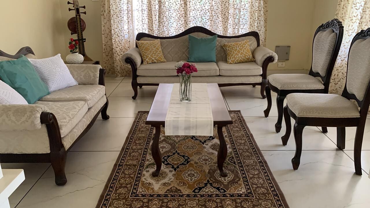 Un salon comprenant un canapé, des fauteuils, une table basse et un tapis à motifs.