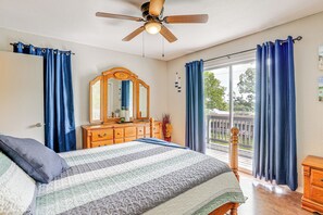 Ein Schlafzimmer mit einem Bett, einem Schminktisch, einem Deckenventilator und Blick ins Freie.