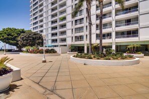 A multi-story hotel with balconies, a central courtyard with palm trees, and a clean, tiled walkway.