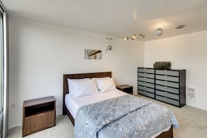 A bedroom with a bed, bedside tables, a dresser, and a wall-mounted light fixture.