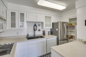 A modern kitchen with white cabinetry, a stainless steel refrigerator, a built-in dishwasher, and a microwave.