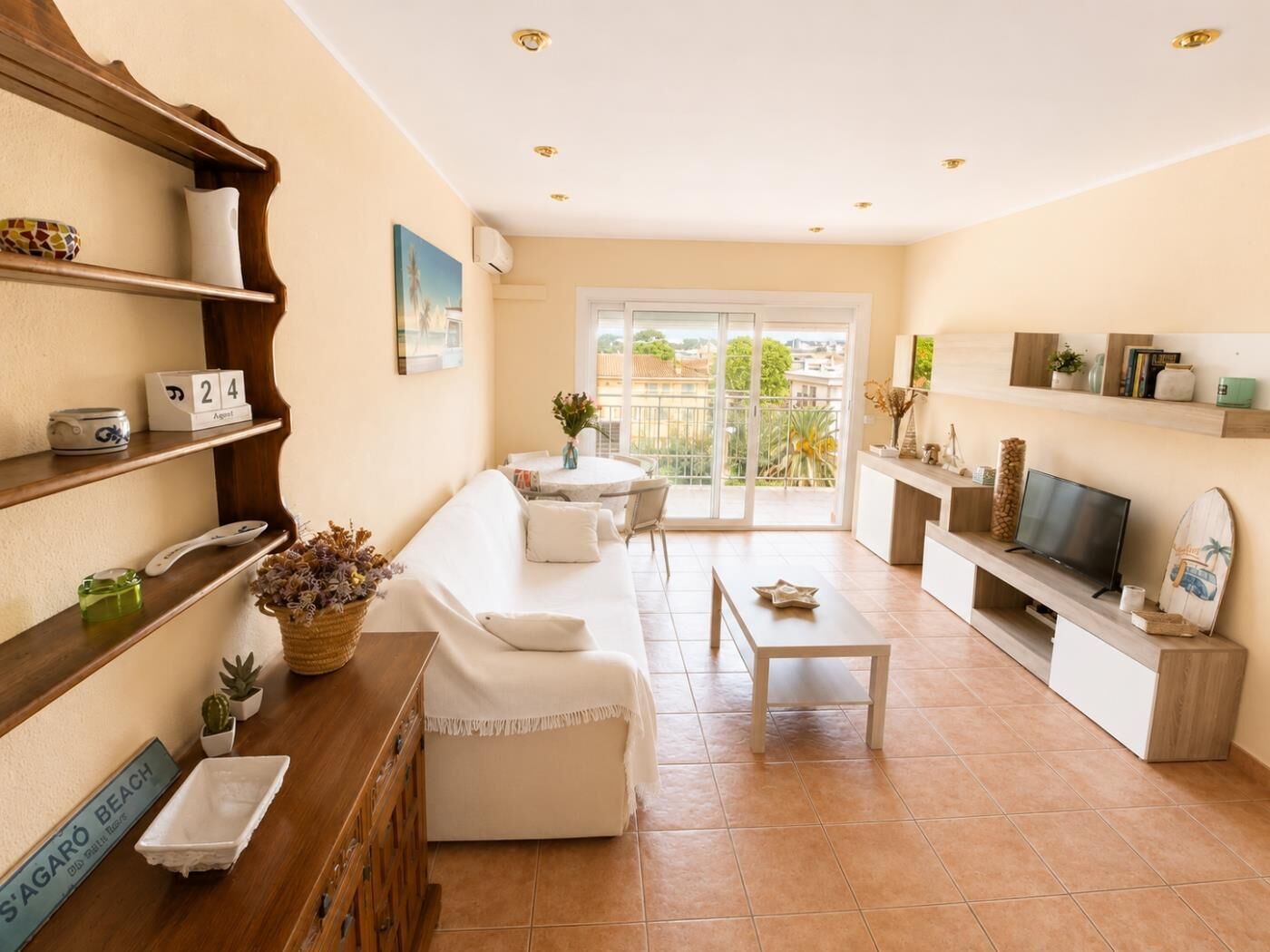 Una sala de estar con sofá, mesa de centro, televisor y balcón con vistas.