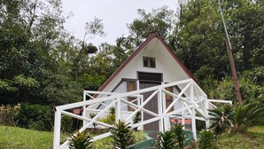 A white building with a red roof, surrounded by greenery and yellow flowers. - Tranquil Cabin Getaway in San Ramón, Costa Rica (San Ramón)