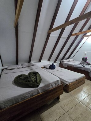 A dormitory room with two beds, wooden beams, and a tiled floor. - private and pleasant (zapotal)