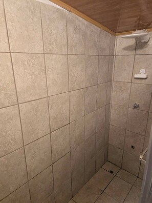 A tiled shower stall with a wooden ceiling.