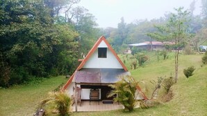 A small, single-story house with a sloped roof, surrounded by a grassy area and trees. - private and pleasant (zapotal)