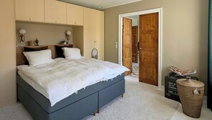 A bedroom with a bed, wardrobe, bedside lamps, and a small table with a lamp. - Light apartment with classic details in Copenhagen (København)