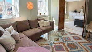A modern living room with a sectional sofa, a glass coffee table, and a patterned rug. - Light apartment with classic details in Copenhagen (København)