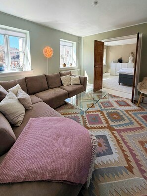 Una sala de estar moderna con un sofá modular, una mesa de centro de vidrio y un tapete estampado.