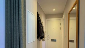 A hallway with a door, a coat rack, a mirror, and a carpeted floor. - Light apartment with classic details in Copenhagen (København)