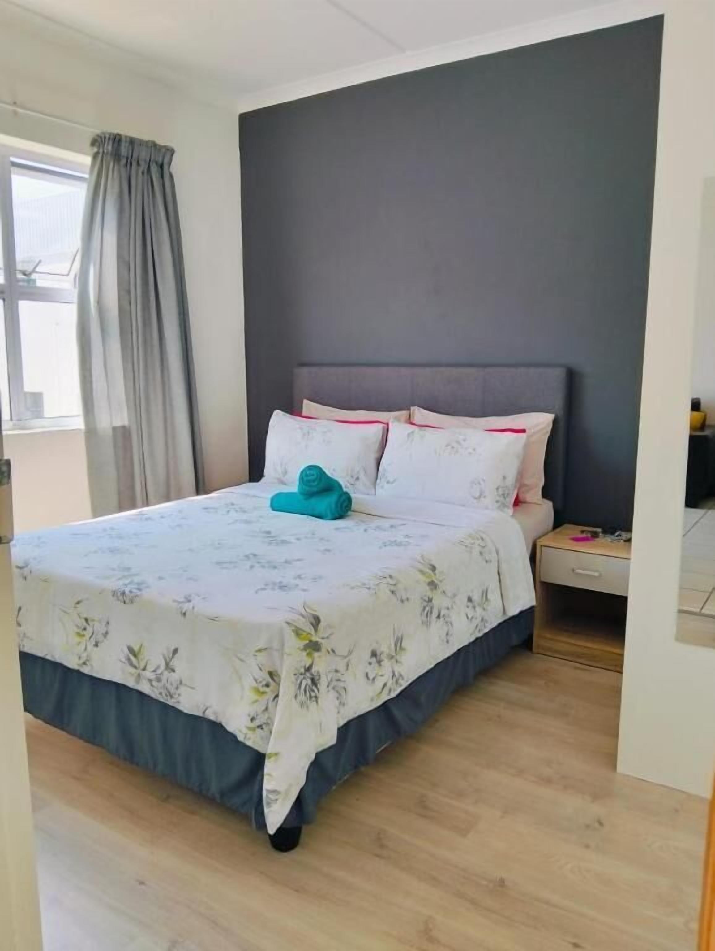 A bedroom with a bed, a nightstand, and a window with curtains.