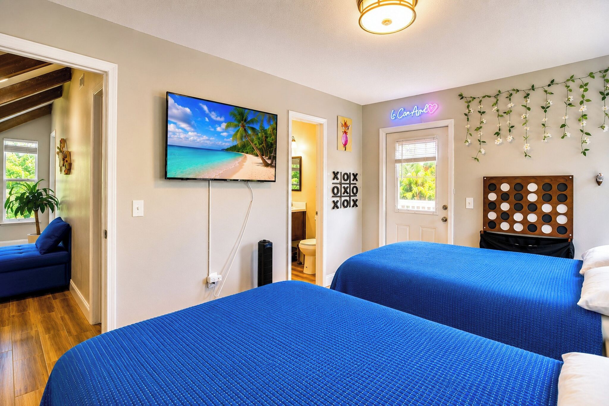 Ein Zimmer mit zwei Betten, einem an der Wand befestigten Fernseher, einer Tür mit Fenster und einer Wanddekoration.