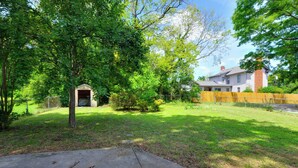 A residential backyard with a wooden shed, a fenced yard, and a house with a chimney. - 1 Mi to UNCG & Dtwn! Group Retreat w/ Private Yard (Greensboro)