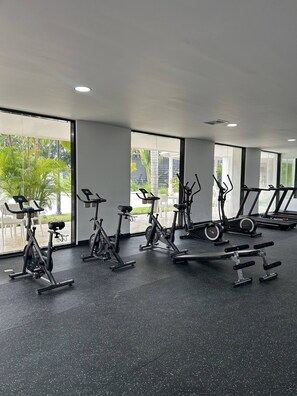 A gym with stationary bikes, treadmills, and a bench press. - Soreli•Peaceful Retreat at Green One Playa Dorada (Puerto Plata city)