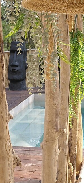 A pool area with wooden pillars and a large stone sculpture in the background. - Exceptional, charming home with a private and exclusive pool (La Motte)