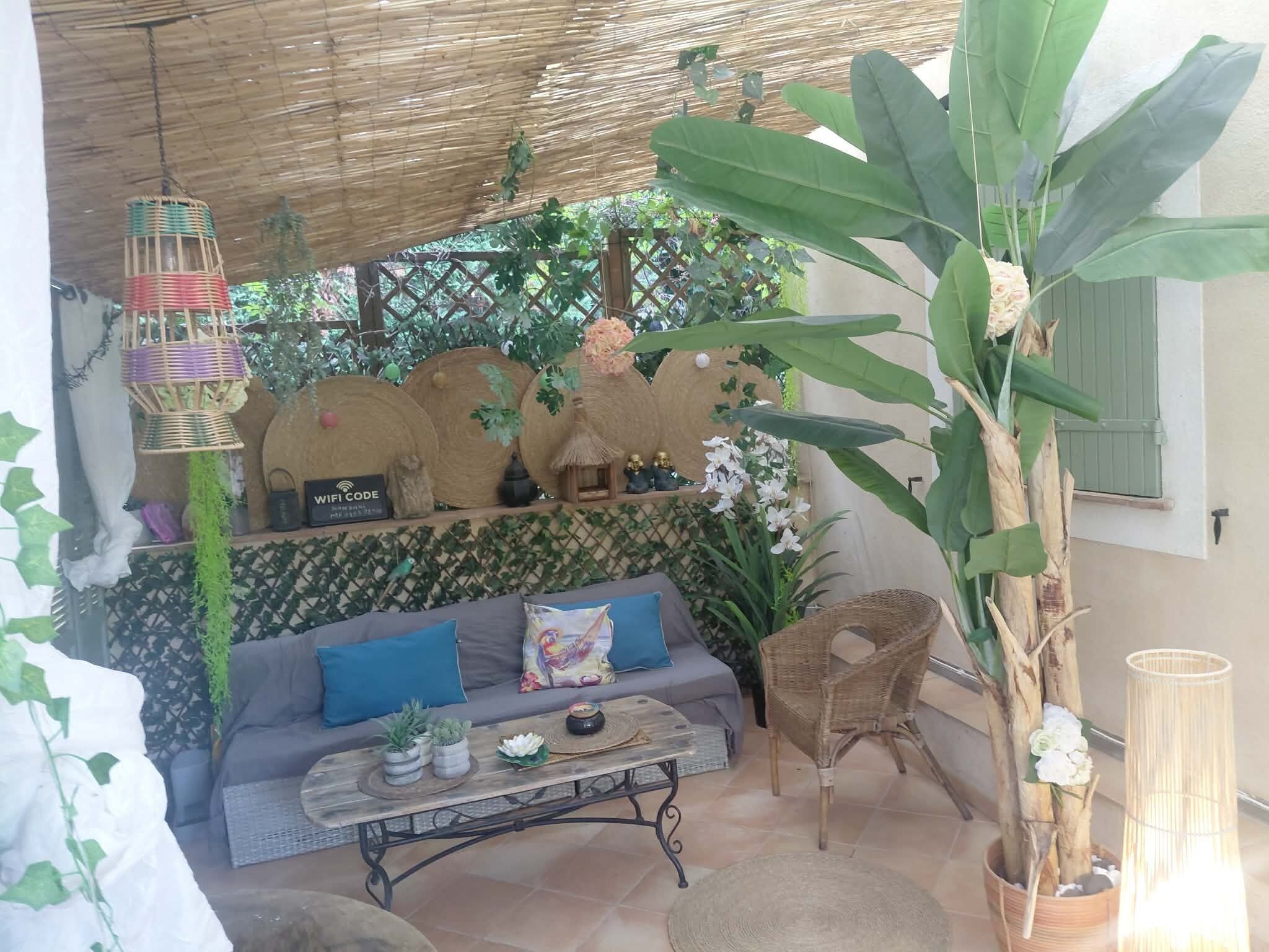 Un espacio al aire libre acogedor con un sofá, una mesa de centro y una silla de mimbre.