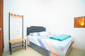 A single bed with a grey headboard, a bench, and a wall-mounted light fixture. - Cozzy Villa Andela (batu)
