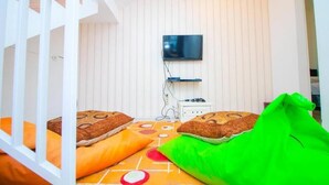 Ein Zimmer mit einem Etagenbett, einem an der Wand montierten Fernseher und einer Steckdose.