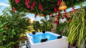 A hot tub surrounded by lush greenery and a wooden fence.