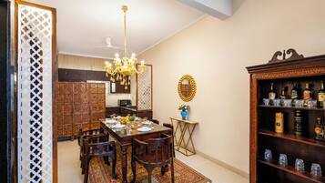 A dining area with a chandelier, a wooden cabinet with bottles, and a decorative mirror.