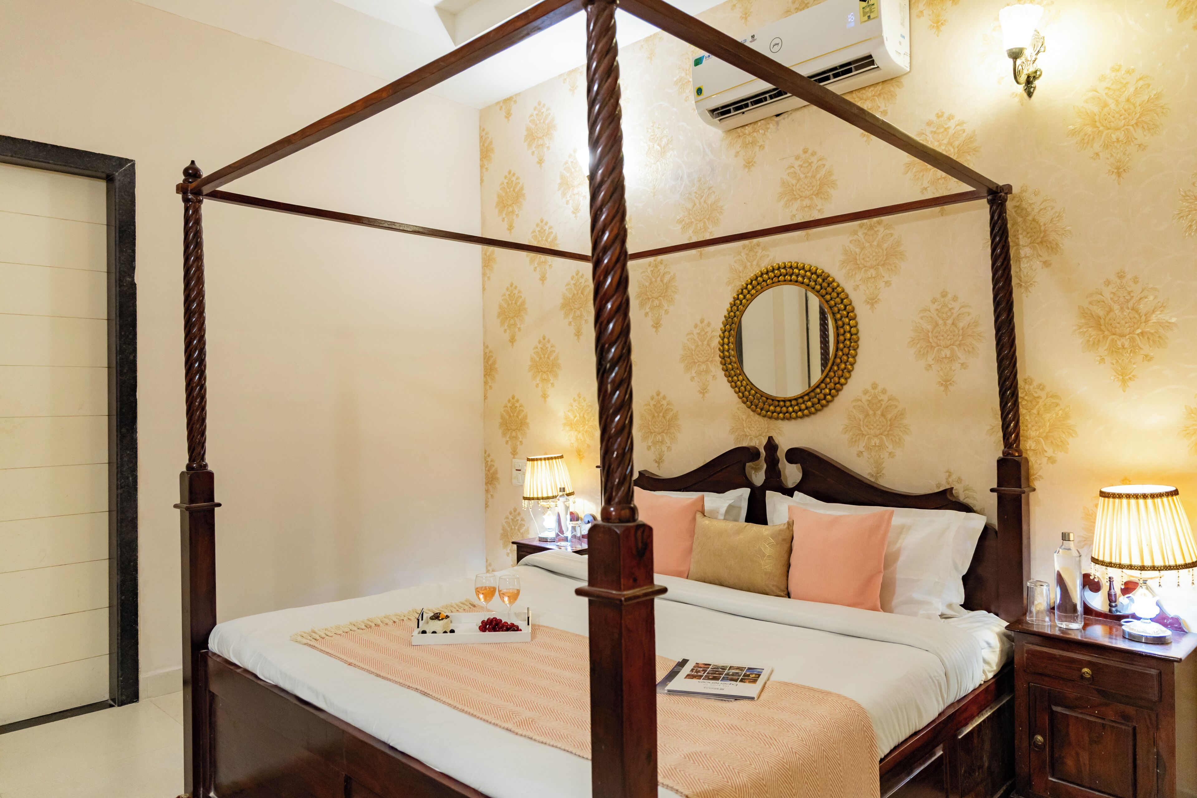 A four-poster bed with a wooden frame, a bedside table with a lamp, and a wall-mounted mirror.