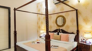 A four-poster bed with a wooden frame, a bedside table with a lamp, and a wall-mounted mirror.