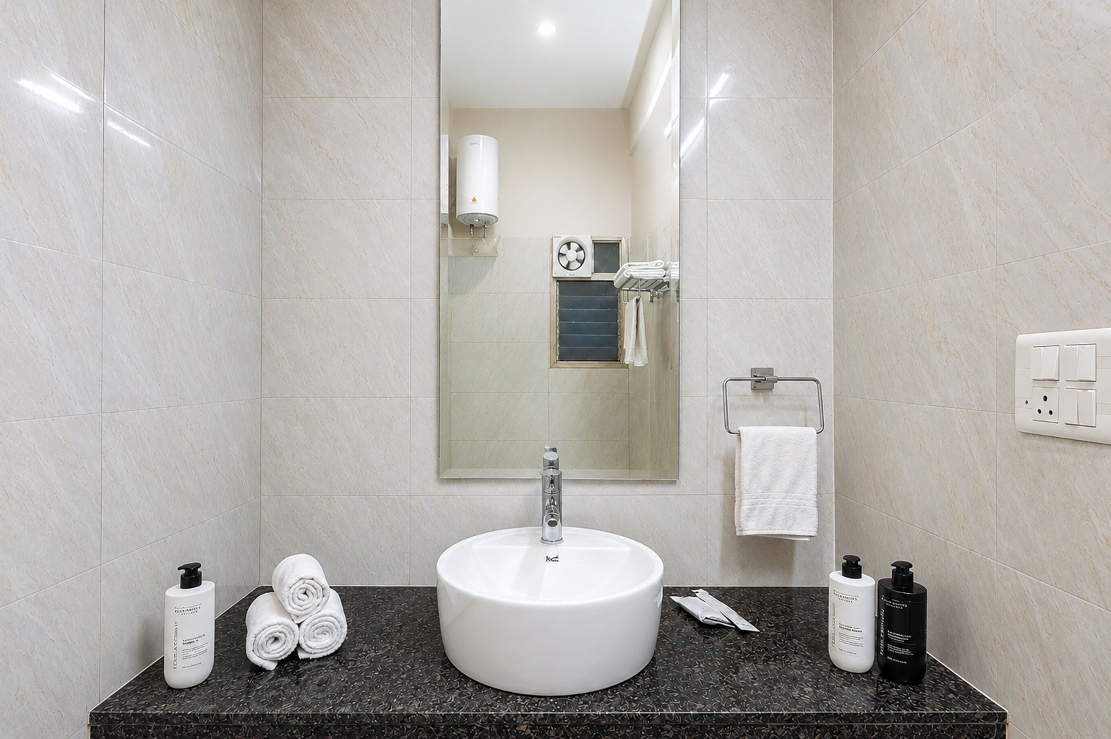 Un bagno moderno con un lavandino bianco, uno specchio e un porta asciugamani.