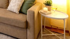 A living room with a sofa, a small round table, a lamp, and a framed picture on the wall. - Casa Alfama Apartment (Lisboa)
