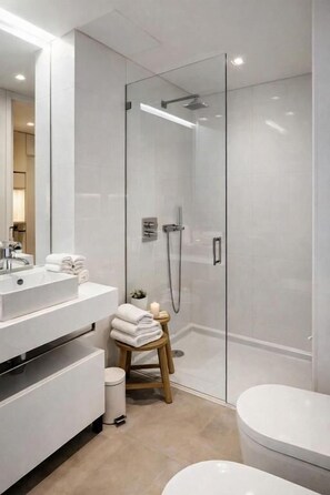 Ein modernes Badezimmer mit einer gläsernen Duschkabine, einem weißen Waschbecken und einer Toilette.