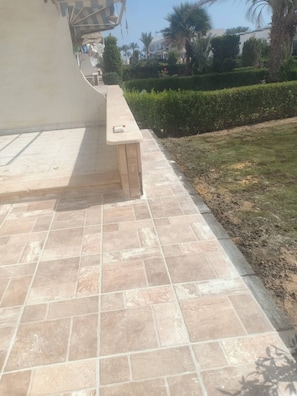 A paved outdoor area with a bench and a wall.
