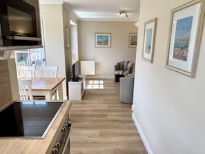 A modern kitchen with a built-in oven and a dining area with a table and chairs. - Eidumweg Apartment 3 - Bright and modern ground-floor apartment for 2 people with (Sylt)
