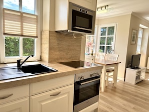 A modern kitchen with a built-in oven, a microwave, and a sink. - Eidumweg Apartment 3 - Bright and modern ground-floor apartment for 2 people with (Sylt)
