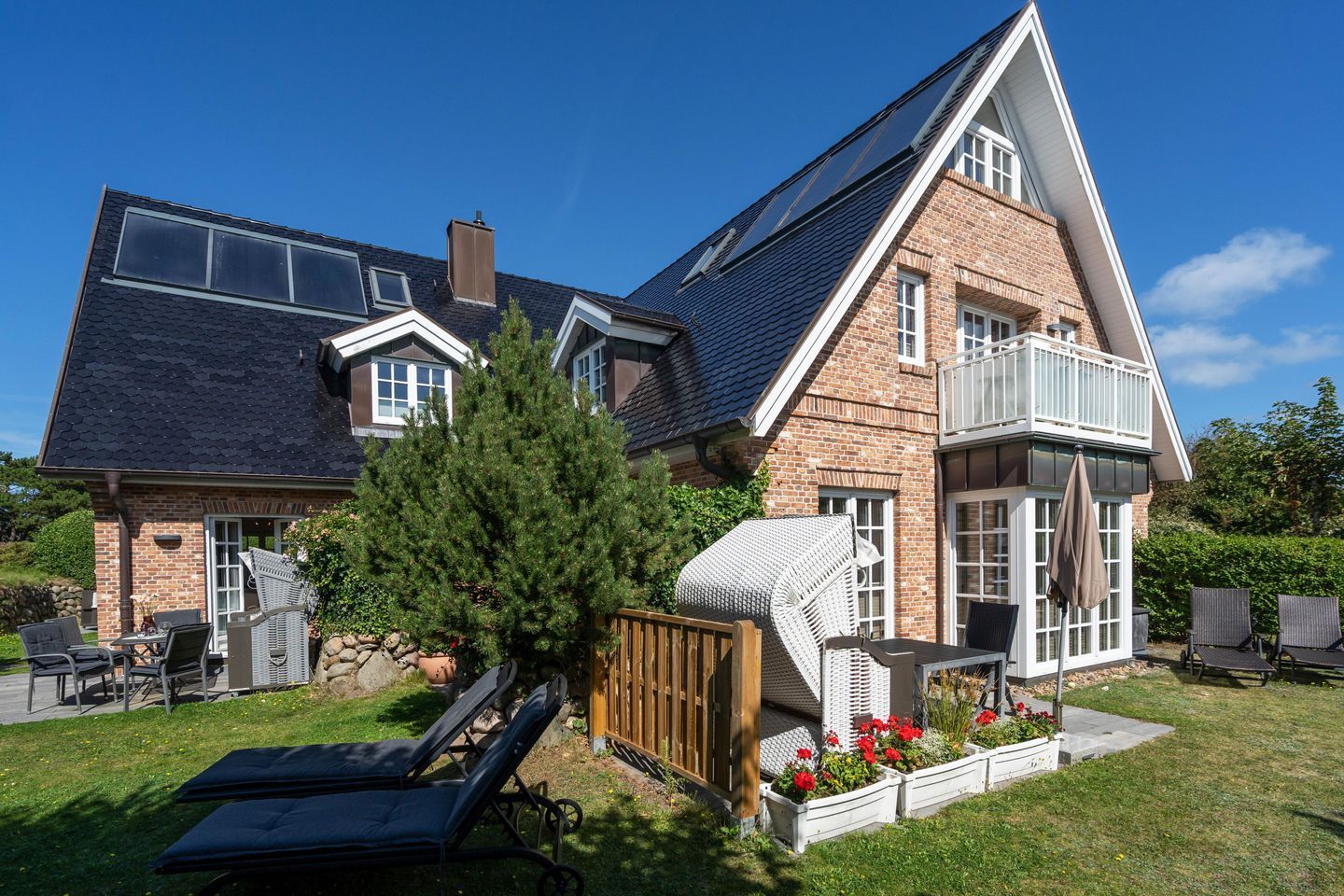 Ein zweigeschossiges Haus mit geneigtem Dach, einer Ziegel-Fassade und einem Balkon.